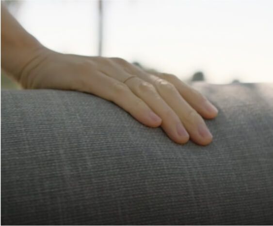 Hand resting on a cushioned outdoor fabric surface, showing upholstery texture and softness in natural light