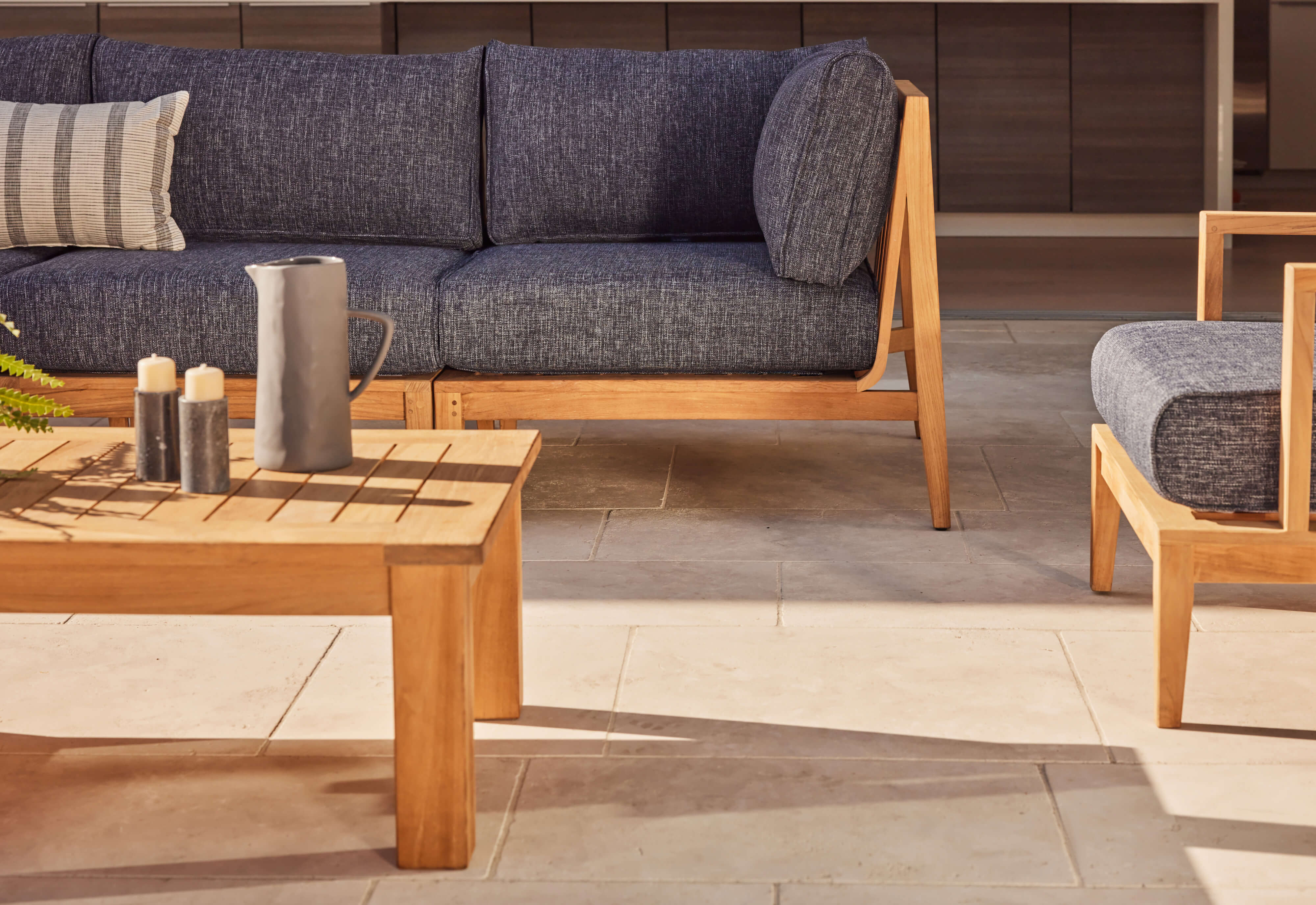 Teak outdoor loveseat with navy blue cushions, featuring a sturdy wooden frame and comfortable seating, set on a wooden deck.-teak outdoor sofa-outer