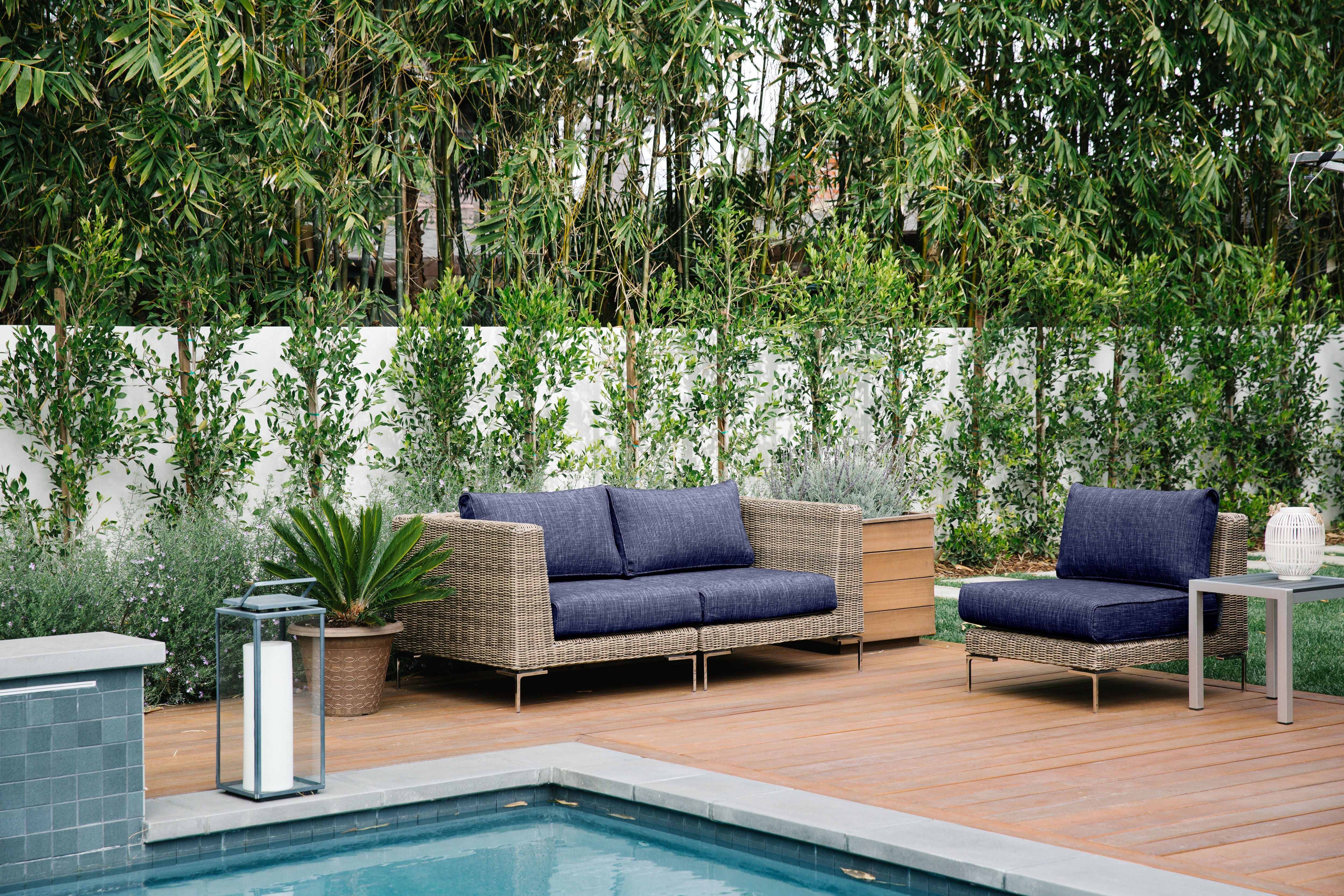 The brown all-weather wicker loveseat and armless chair in navy fabric featured poolside. 